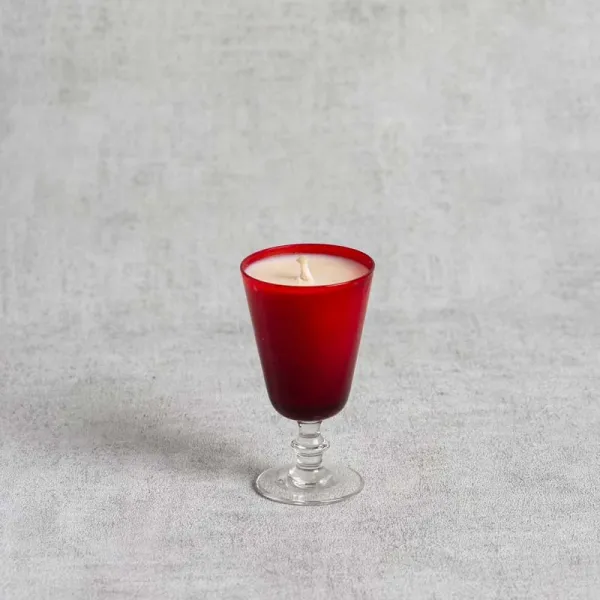Bougie parfumée dans un verre à pied rouge élégant.